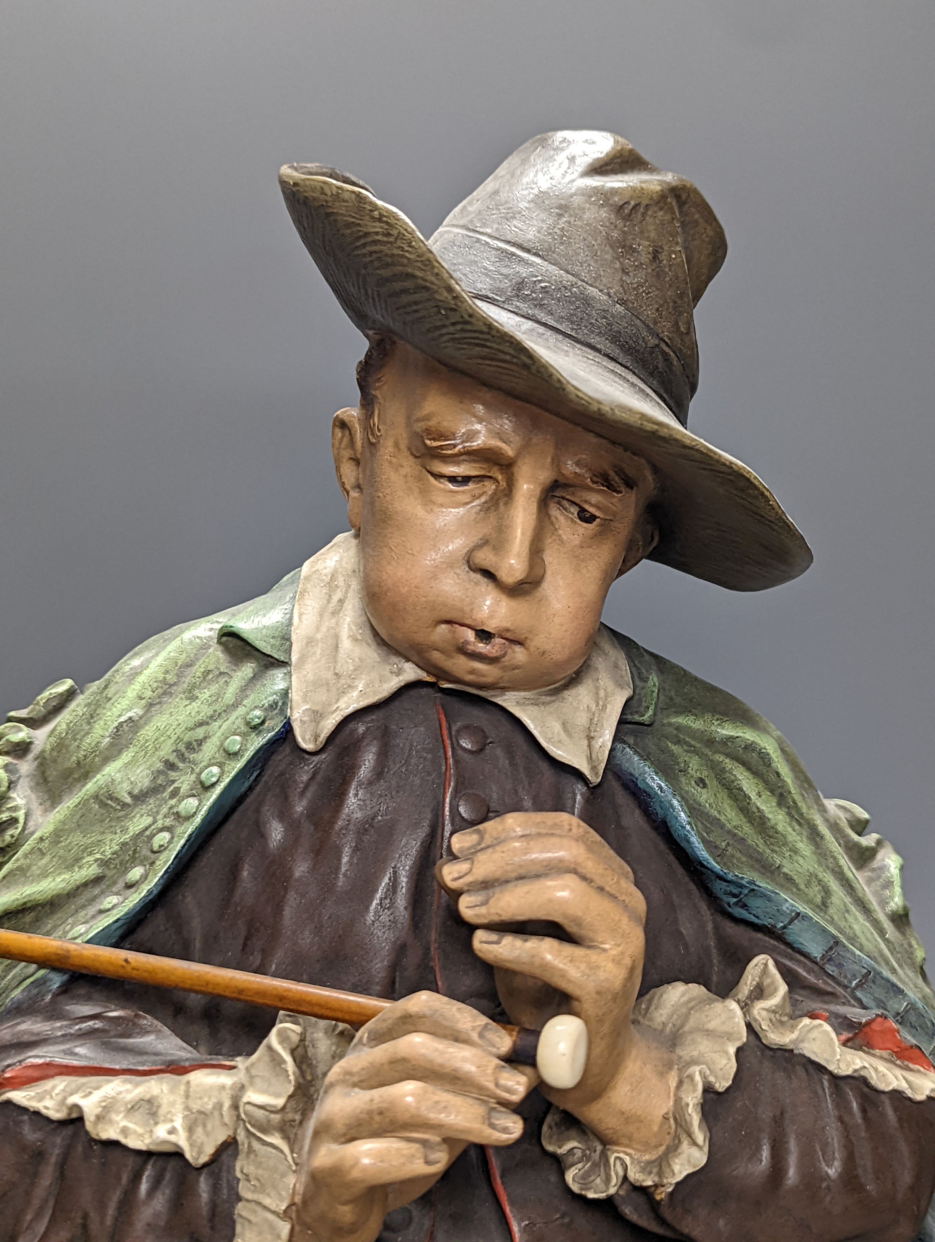 A pair of late 19th/early 20th century Austrian cold painted terracotta figures of musicians in 17th century dress, seated on wood stools 46cm